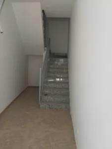Escalera interior de piedra con barandilla metálica y suelo de baldosas